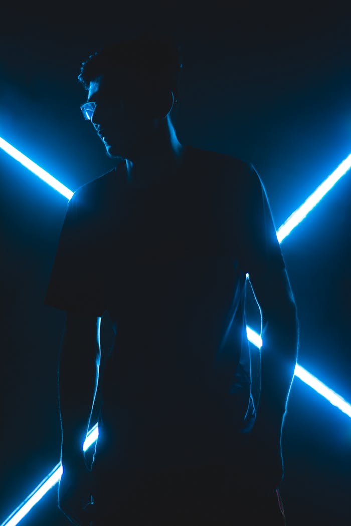 A man silhouetted against glowing blue neon lights creating a futuristic look.
