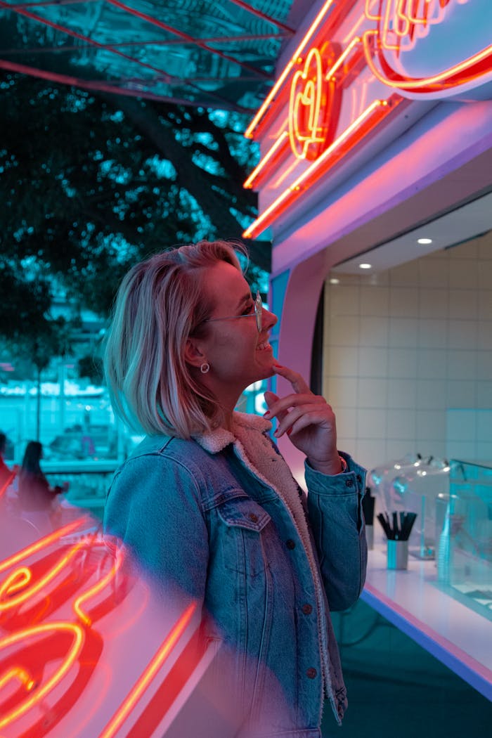 Woman enjoys neon atmosphere at an outdoor food stall in Stockholm.