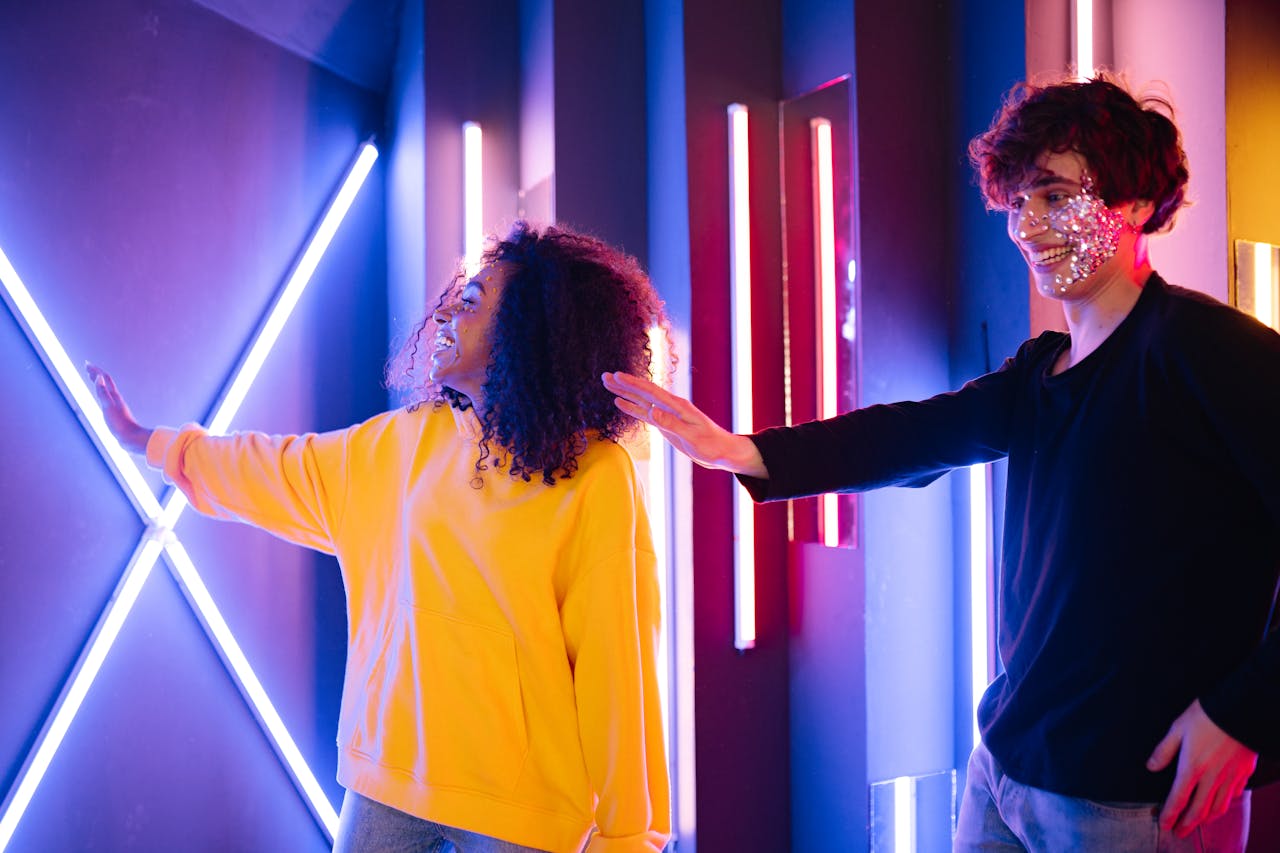 Two people enjoying neon lights, showcasing creative makeup and style.