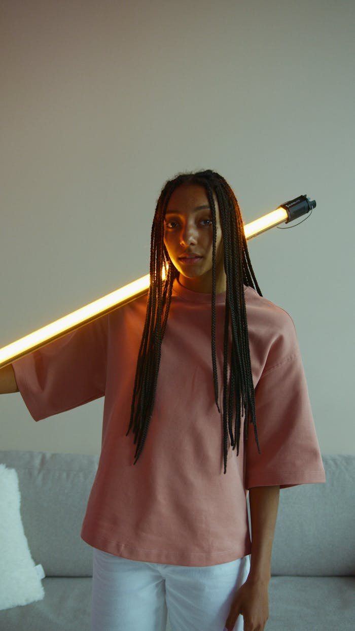 Creative portrait of a young woman holding a glowing LED light in a modern setting.